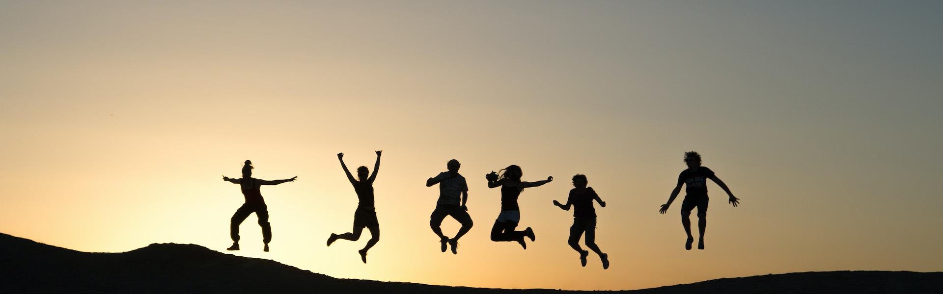 people jumping of the sand dune