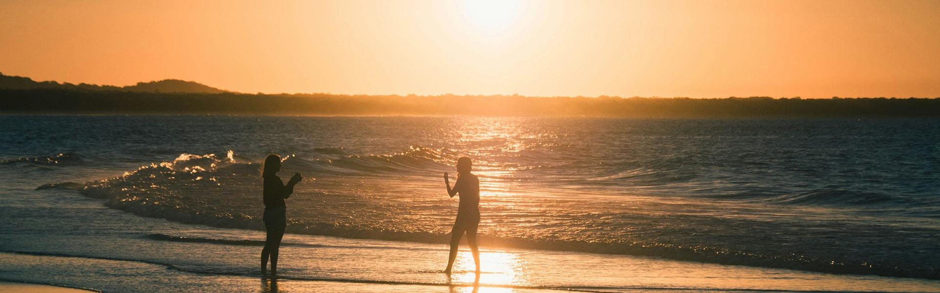 people standing in waters edge at beach